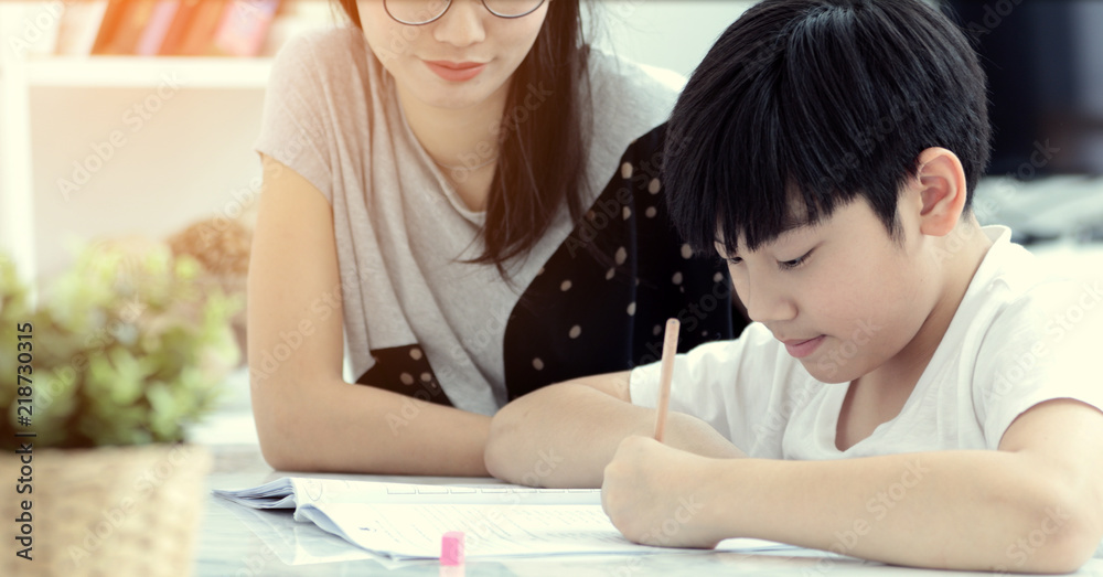 Asian mother with son doing homework in living room. Asian mother with son doing homework in living room.