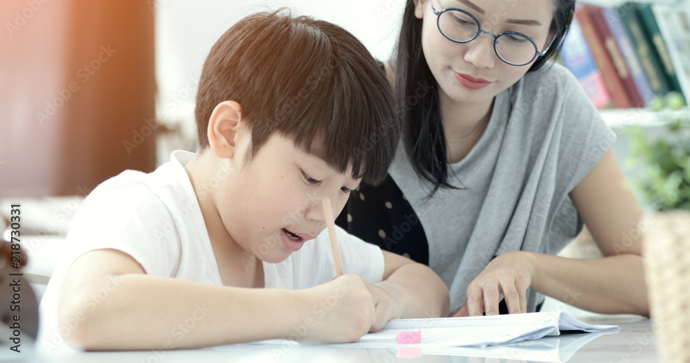 Asian mother with son doing homework in living room. Asian mother with son doing homework in living room.