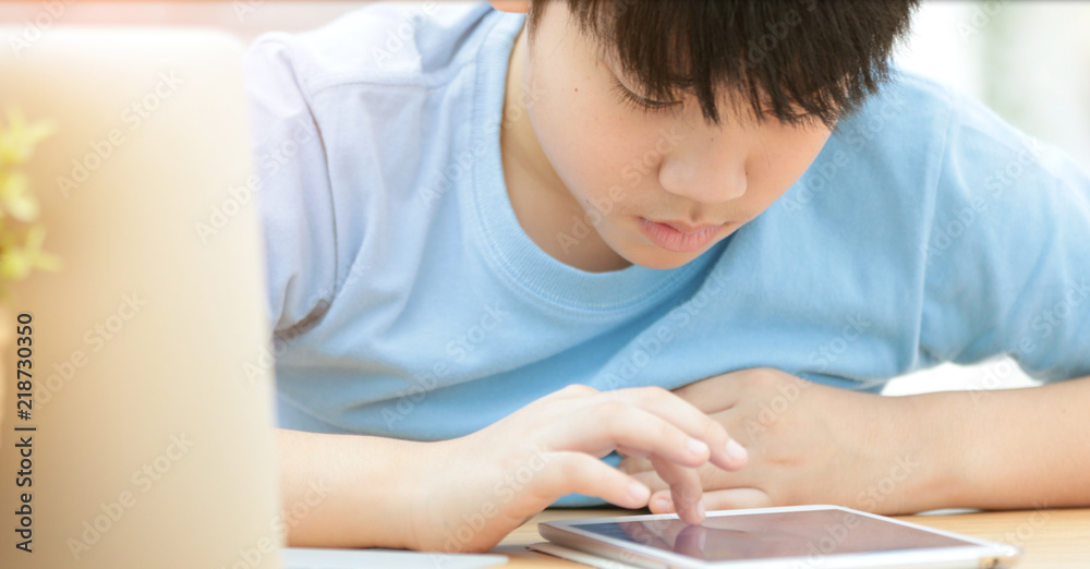 Cute asian boy watch and playing on tablet computer . Cute asian boy watch and playing on tablet computer .