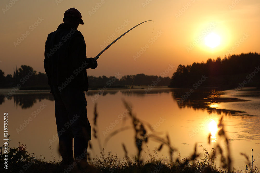 Fisherman with a fishing rod in the morning at dawn