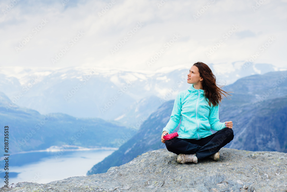 Back of adventurous sportive girl hiker looks at the sky, sitting and relaxing with fjord landscape in beautiful Norway mountains. Back of adventurous sportive girl hiker looks at the sky, sitting and relaxing with fjord landscape in beautiful Norway mountains.