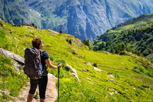 Quadro su tela Female traveler with backpack hiking mountain trail and admiring views of Swiss Alps in Val de Bagnes area, Switzerland