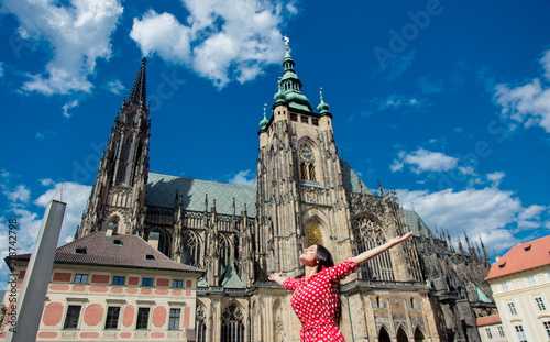 Beautiful girl in red dress travel in Prague, Church on background
