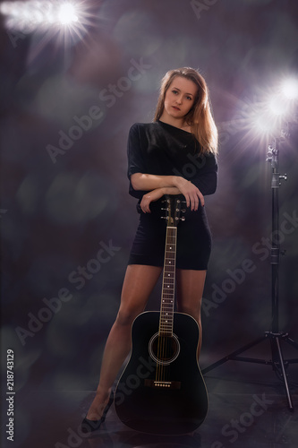 Beautiful girl with guitar on black background.