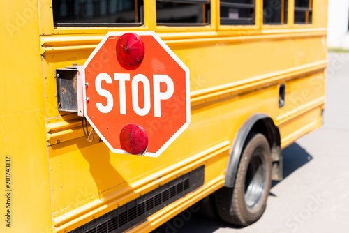 cropped shot of traditional school bus with stop road sign photo