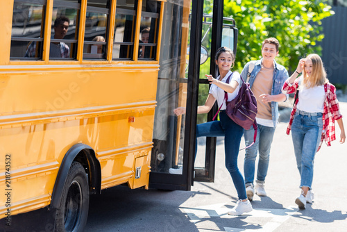 happy teen students walking into school bus