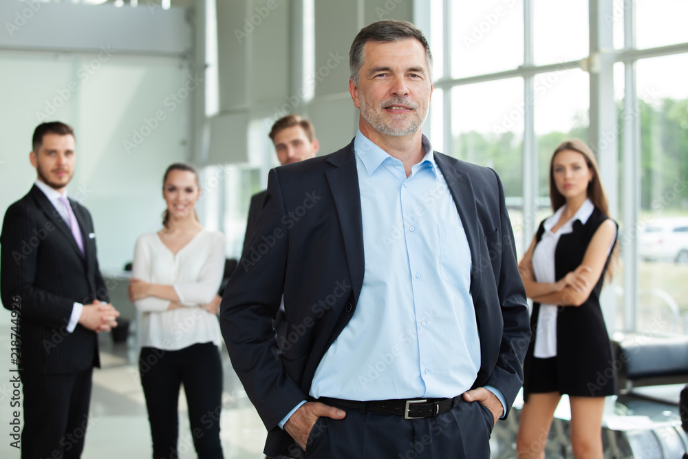 Mature smiling business manager crossing his arms in front of his business team. Mature smiling business manager crossing his arms in front of his business team.