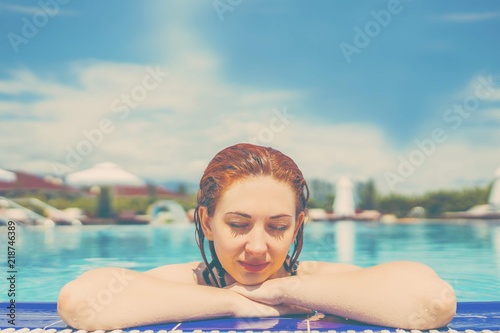 Woman relaxing and hanging on the railing of pool.