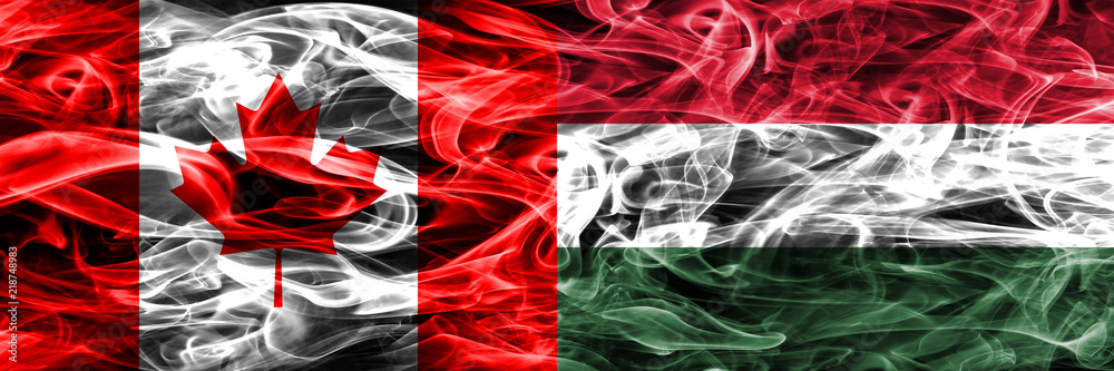 Obraz premium Canada vs Hungary smoke flags placed side by side. Canadian and Hungary flag together