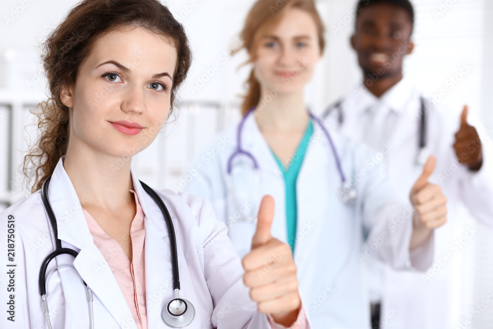 Medical team of confident doctors showing Ok sign with thumbs up. Medicine and health care, insurance concept Medical team of confident doctors showing Ok sign with thumbs up. Medicine and health care, insurance concept