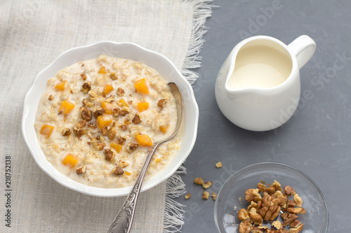 Pumpkin oatmeal with honey and nuts, milk, walnuts on a gray background. healthy delicious homemade breakfast