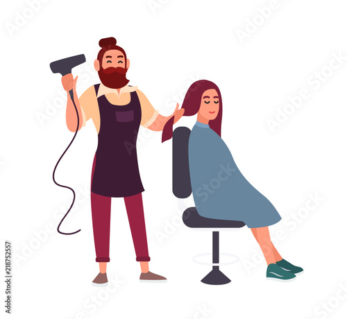 Adorable friendly bearded male hairdresser blow-dry with hairdryer hair of his smiling female client sitting in chair isolated on white background