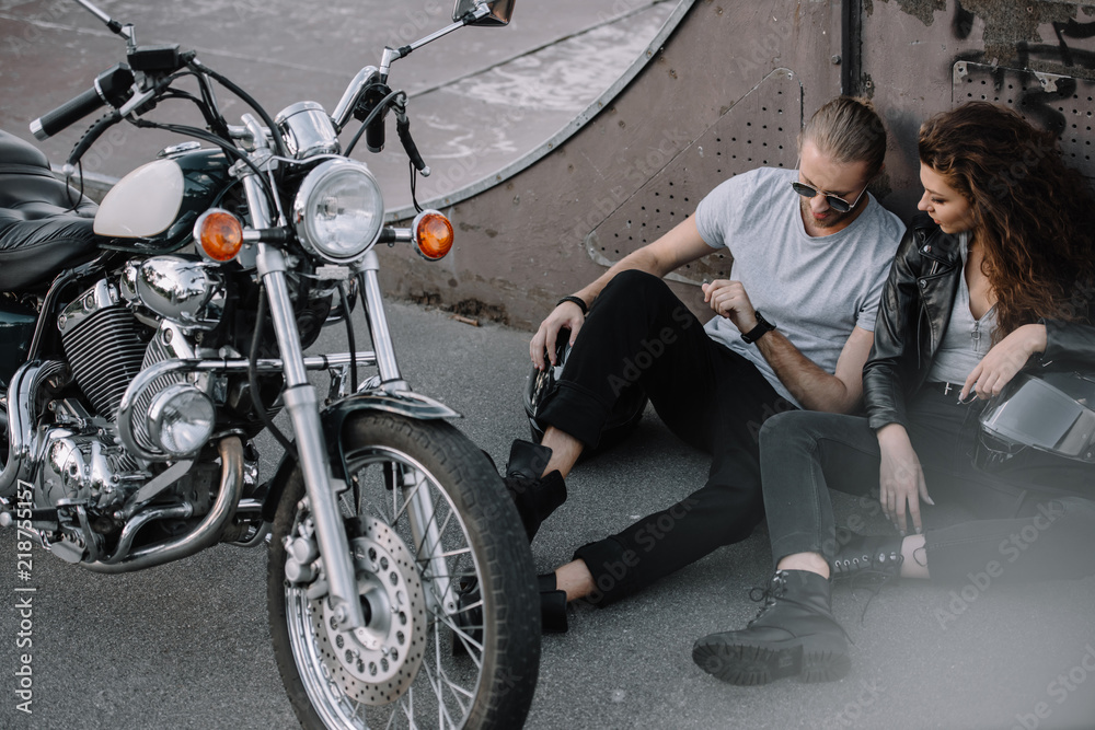girlfriend and boyfriend sitting on asphalt with classical chopper motorcycle girlfriend and boyfriend sitting on asphalt with classical chopper motorcycle