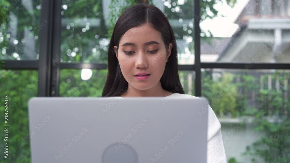 Beautiful young smiling asian woman working on laptop while sitting in living room at home. Asian business woman working document finance and calculator in her home office. Enjoying time at home. Beautiful young smiling asian woman working on laptop while sitting in living room at home. Asian business woman working document finance and calculator in her home office. Enjoying time at home.
