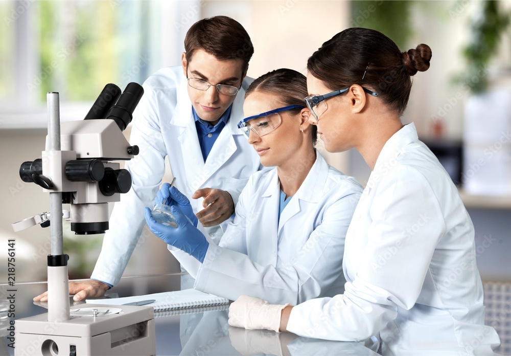 Female and male scientists in glasses working with microscope Female and male scientists in glasses working with microscope