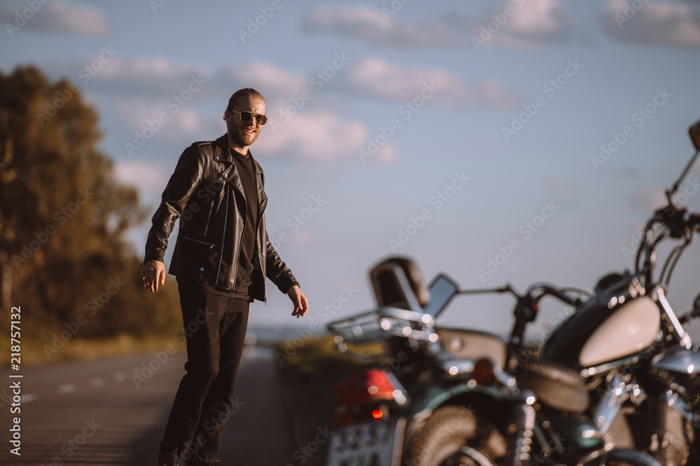 handsome man standing on road with classical motorbike, selective focus