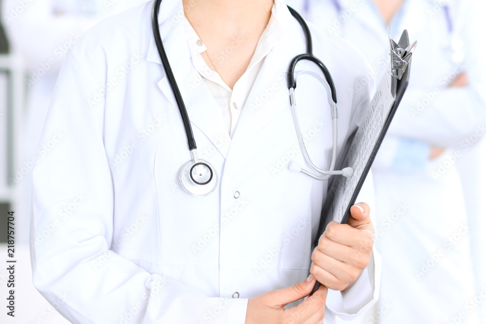 Unknown female doctor with medical staff at hospital. Teamwork in medicine Unknown female doctor with medical staff at hospital. Teamwork in medicine