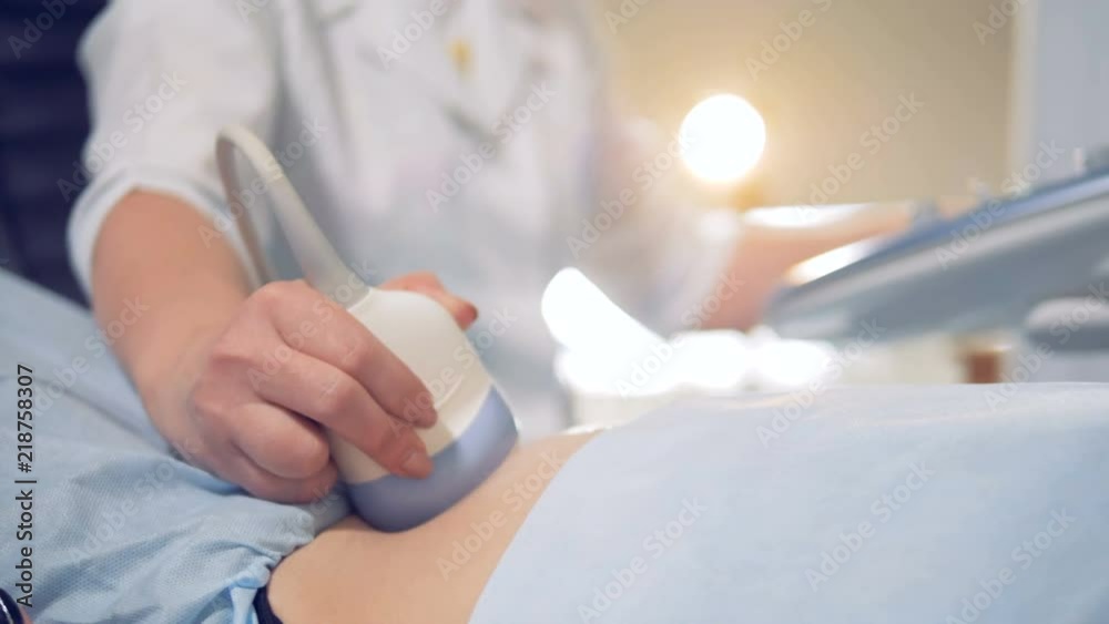 Doctor is guiding a sensor along the belly surface during ultrasound