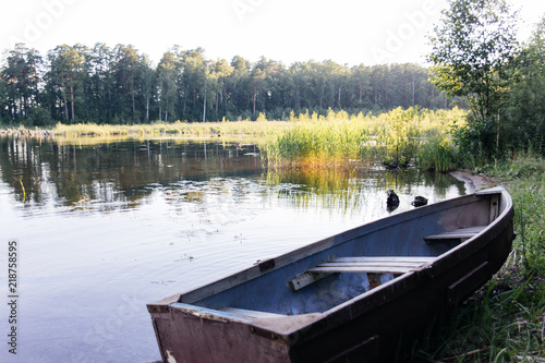 beautiful campsite on a clear lake with a boat © Nichizhenova Elena