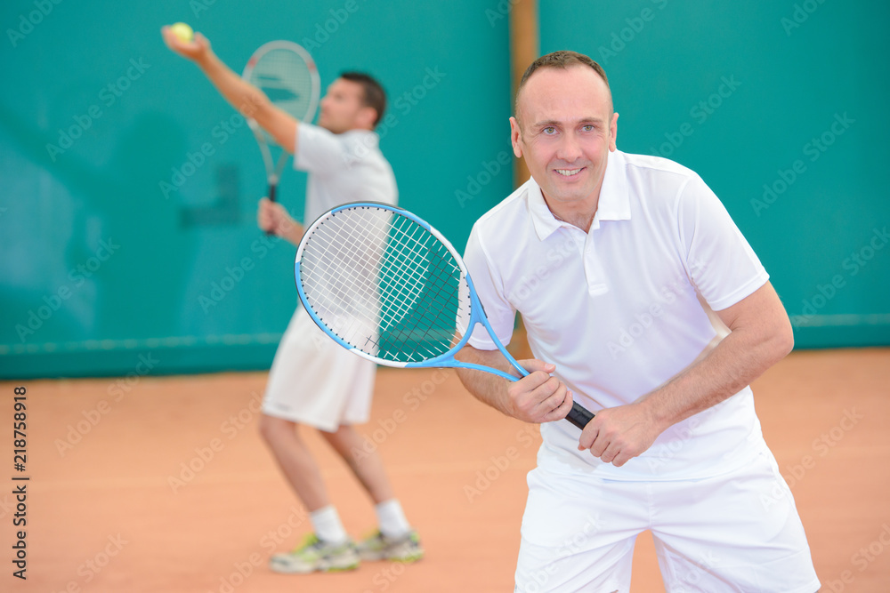 Men playng tennis doubles