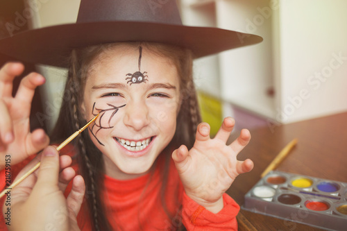 preparation for the celebration of Halloween. child in a witch outfit doing face painting. cute spider. idea of simple suit, diy, toned photo