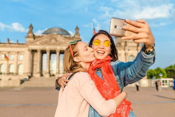 Two happy woman making selfie on background of Reichstag Bundestag building in Berlin. Travel and love concept in Europe