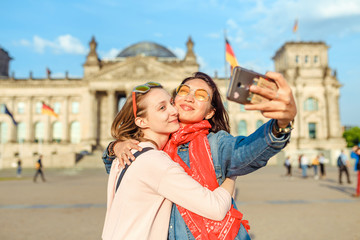 Two happy woman making selfie on background of Reichstag Bundestag building in Berlin. Travel and love concept in Europe