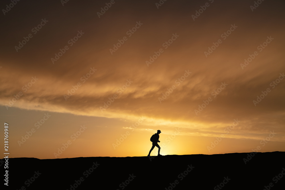 SIlhouette of a lonely woman walking at sunset on a hill