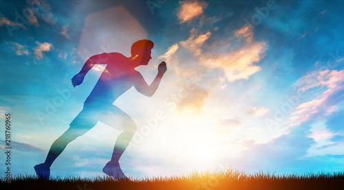 Muscular man running fast on the meadow in a sunset.