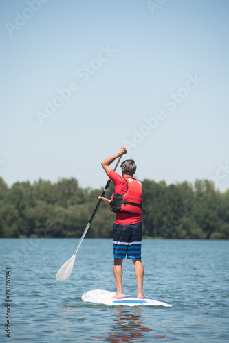 man enjoying a ride on the lake with paddleboard