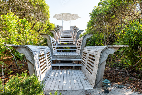 Fototapeta Naklejka Na Ścianę i Meble -  Closeup of wooden pavilion stairs leading to beach ocean with umbrella going up steps in Florida, sand, green shrubs, plants, nobody empty landscape view during sunny day