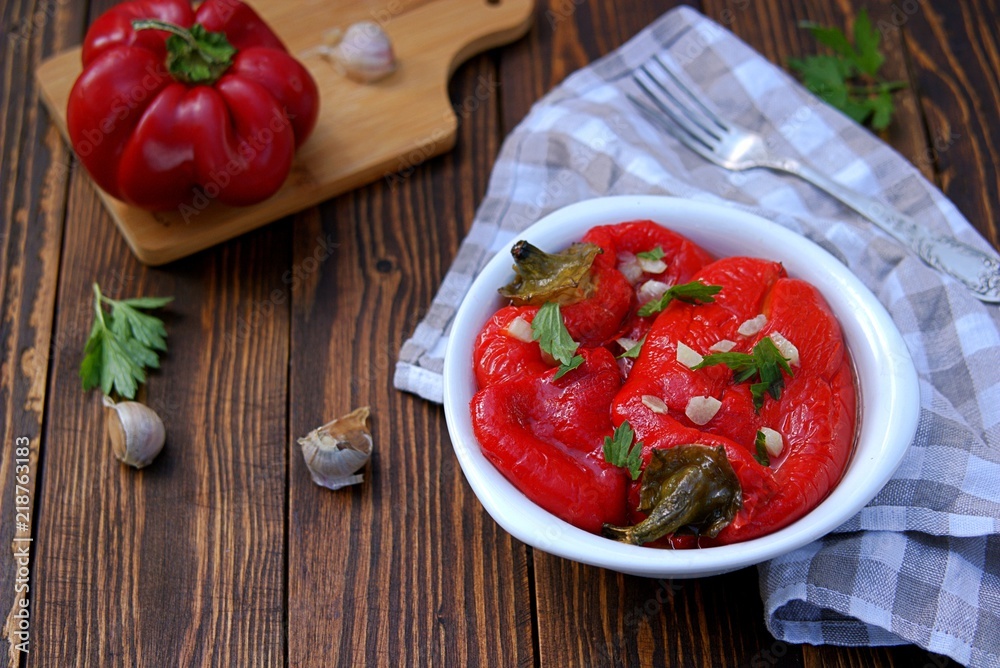 Appetizer, roasted pickled sweet red pepper in a white bowl on a wooden background. Serbian cuisine. Appetizer, roasted pickled sweet red pepper in a white bowl on a wooden background. Serbian cuisine.