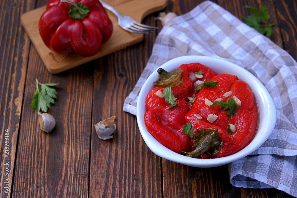 Appetizer, roasted pickled sweet red pepper in a white bowl on a wooden background. Serbian cuisine. Appetizer, roasted pickled sweet red pepper in a white bowl on a wooden background. Serbian cuisine.