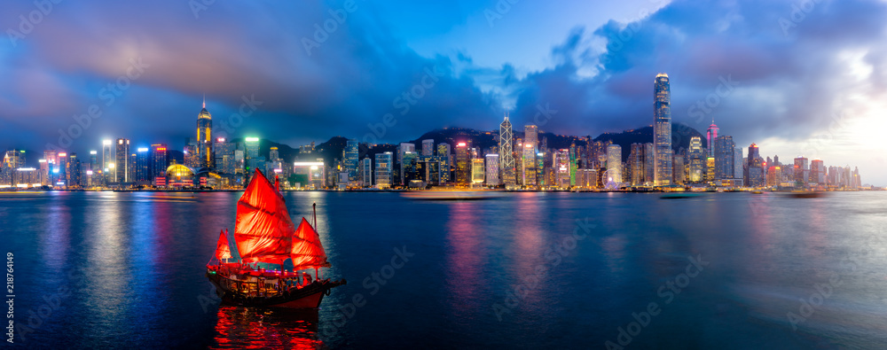 Fototapeta premium Panorama panoramę Hongkongu z turystyczną żaglówką w nocy. Widok z całej Victoria Harbour HongKong.
