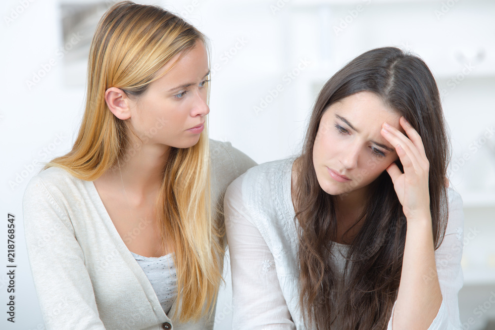 girl supporting her depressed female friend indoors girl supporting her depressed female friend indoors