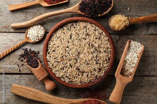 Different types of rice in kitchenware on wooden table
