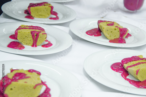 detail aufnahme kuchen dessert mit himbeeren auf weißem teller und hellem untergrund himbeersauce