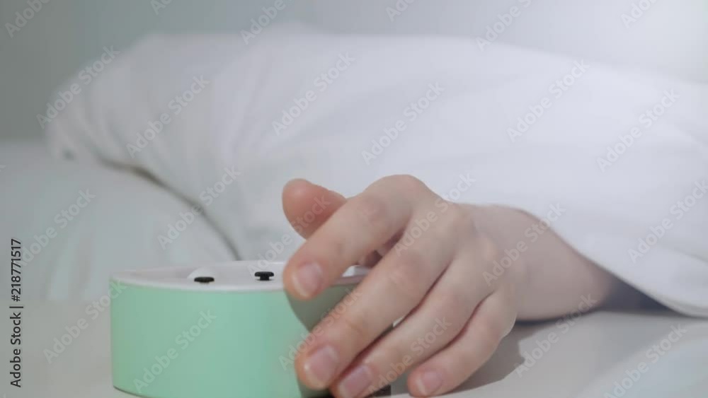 Wake up of an asleep girl stopping alarm clock on the bed in the morning. Wake up of an asleep girl stopping alarm clock on the bed in the morning.