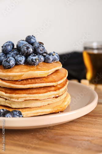 Plate with tasty pancakes and blueberries on wooden table