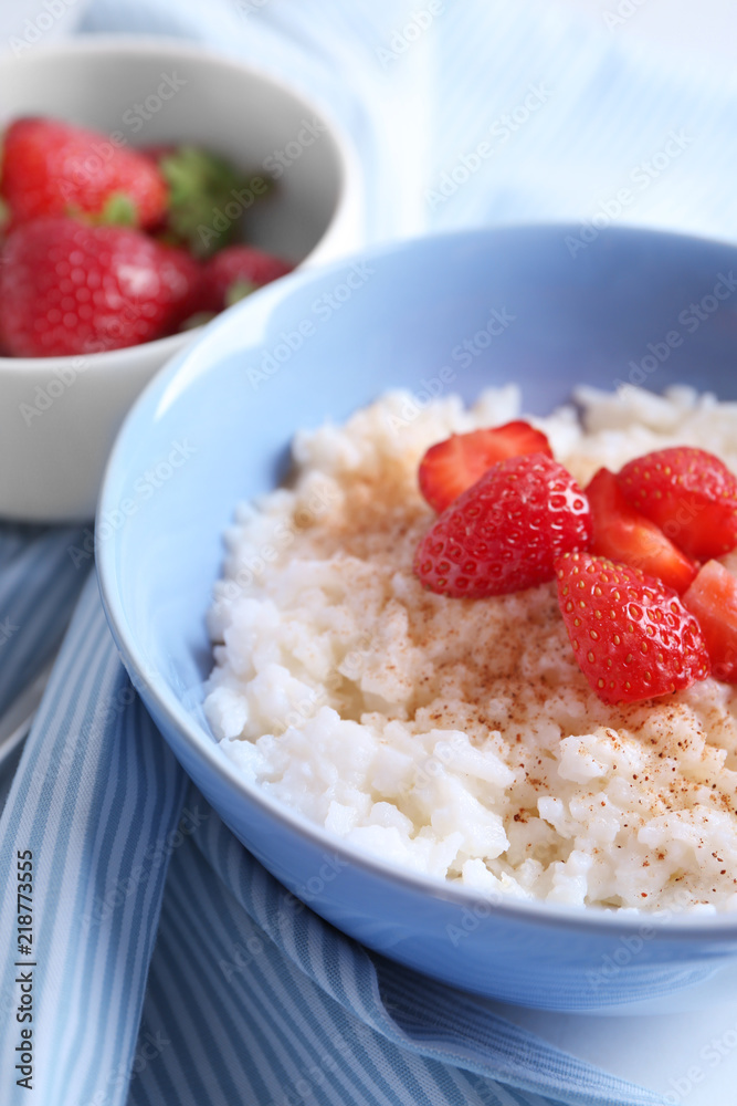 Bowl with delicious rice pudding and strawberry on table, closeup Bowl with delicious rice pudding and strawberry on table, closeup