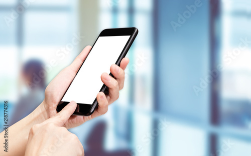 Hand click mobile phone with blur office background bokeh light,White screen mock up template for adding your design or your text.