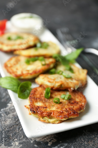 Plate with zucchini pancakes on table, closeup