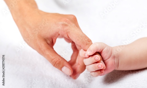 New born baby hand holding kuman hand on white background photo