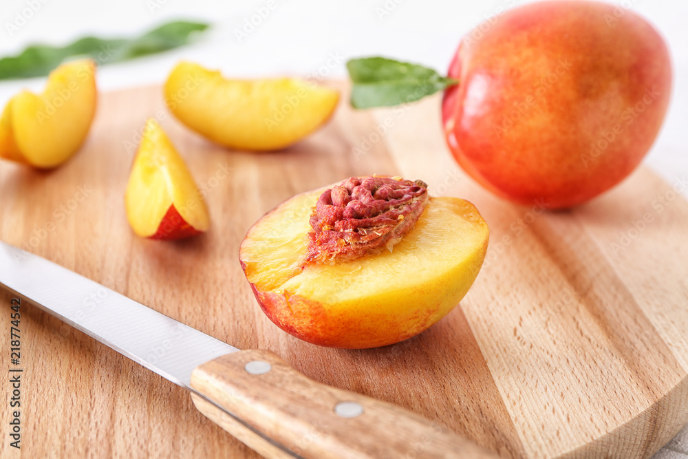 Fresh cut peach with knife on wooden board, closeup