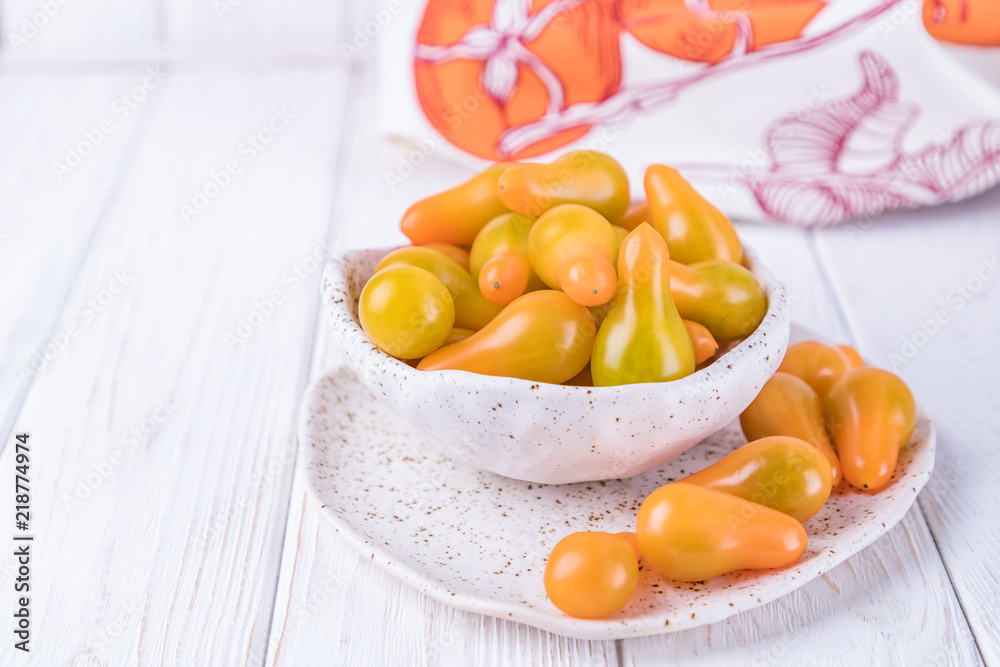 Ceramic bowl with yellow pear tomatoes on white wooden background. Free space Ceramic bowl with yellow pear tomatoes on white wooden background. Free space