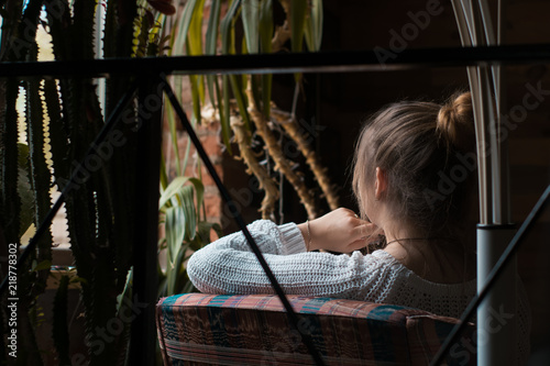 Young girl in white sweater is sitting in the cafe and dreaming