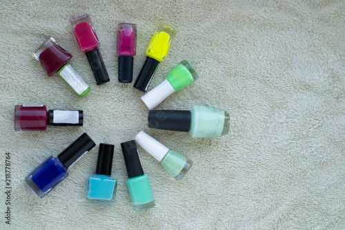 sun rays of colorful nail polish bottles on green background