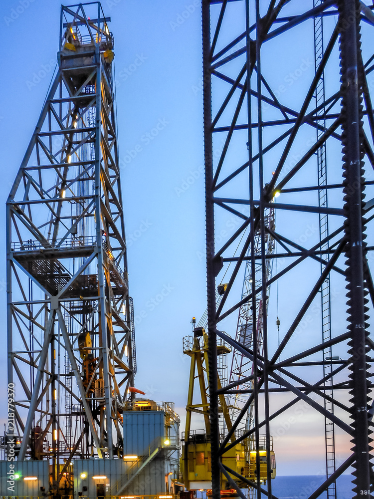 Derrick and crane view in jack up drilling rig with blue sky sunset Derrick and crane view in jack up drilling rig with blue sky sunset