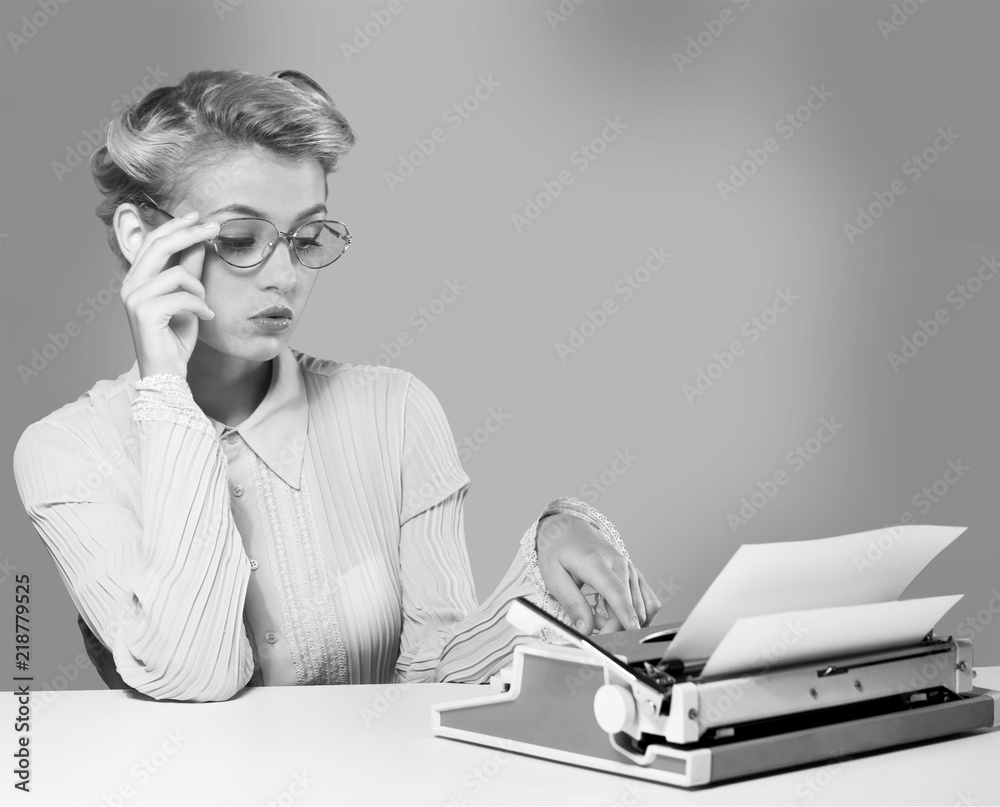 Naklejka premium Młoda blond kobieta pisarz za pomocą maszyny do pisania, czarno-biały