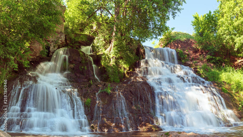 Obraz premium Beautiful mountain rainforest waterfall with fast flowing water and rocks, long exposure. Natural seasonal travel outdoor background in hipster vintage style
